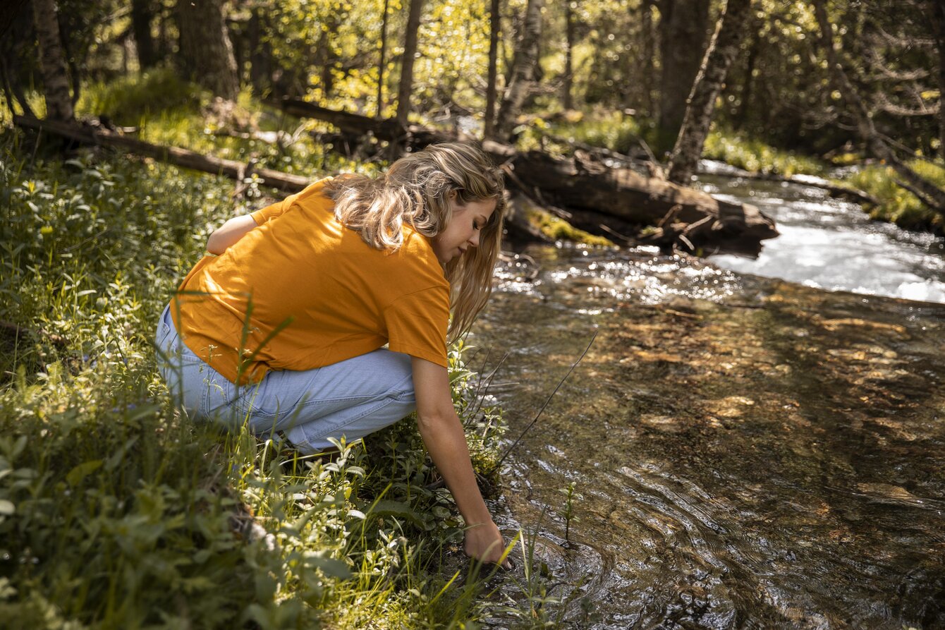 Photo d'illustration : jeune femme préelevant de l'eau dans une rivière